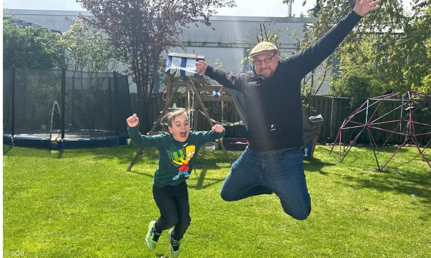 Ein Junge und ein Mann springen im Garten herum