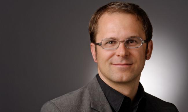 Ein Mann mit Brille, er lächelt
