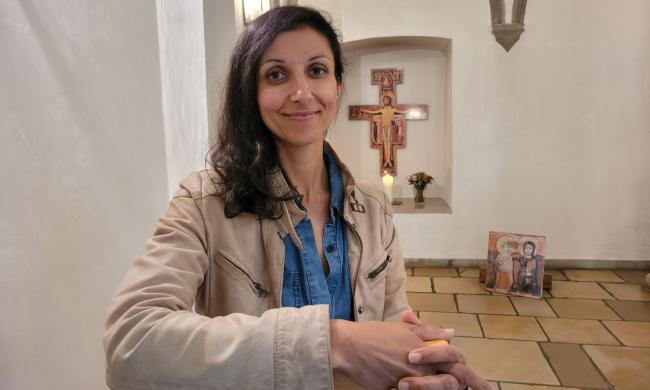 Eine Frau lächelt in einer Kirche in die Kamera