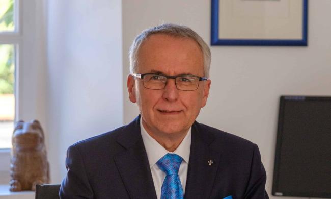 Ein Mann mit Brille und kurzen, grauen Haaren blickt in die Kamera