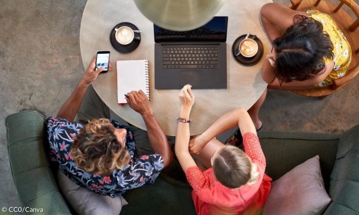 Junge Menschen an einem Tisch mit Laptop und Milchkaffee