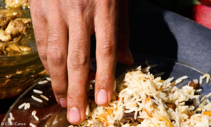 Eine Hand greift in ein Reisgericht