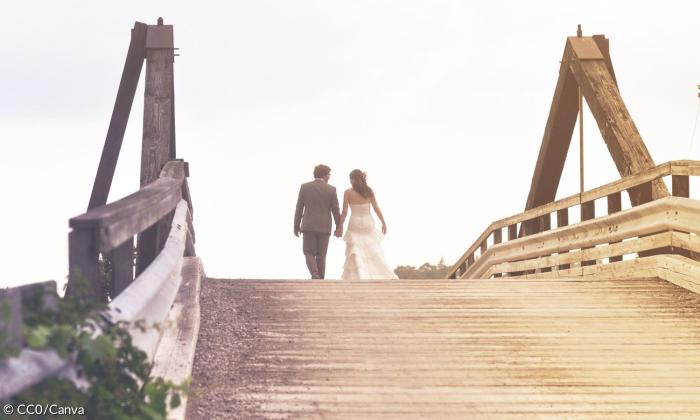 Ein Hochzeitspaar geht über eine Brücke