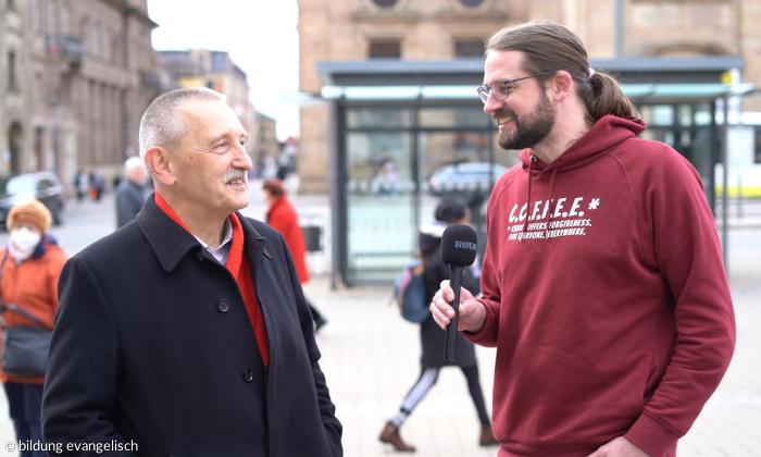 "streettalk"-Moderator Martin spricht mit einem Mann auf dem Erlanger Hugenottenplatz.