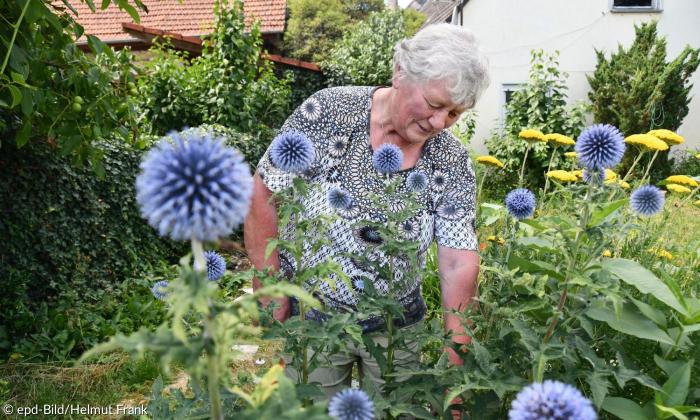 Eine Frau beugt sich über ein Blumenbeet