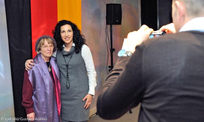 Zwei Frauen vor einer Deutschland-Fahne, ein Mann fotografiert beide