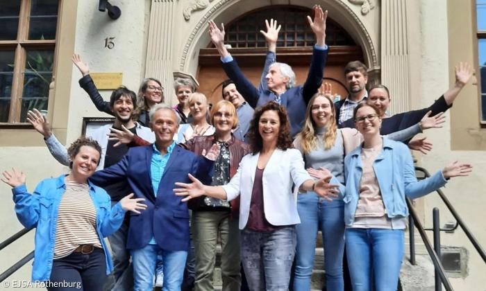 Viele Menschen stehen auf einer Treppe und heben die Arme