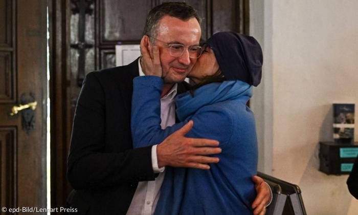 Eine Frau küsst einen Mann auf die linke Backe