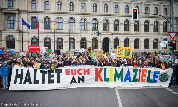 Junge Menschen mit einem Plakat: "Haltet euch an Klimaziele"