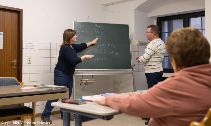 Menschen stehen an einer Tafel, auf der Worte auf Deutsch stehen
