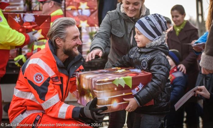 Ein Paket aus dem Weihnachtstruck der Johanniter wird überreicht