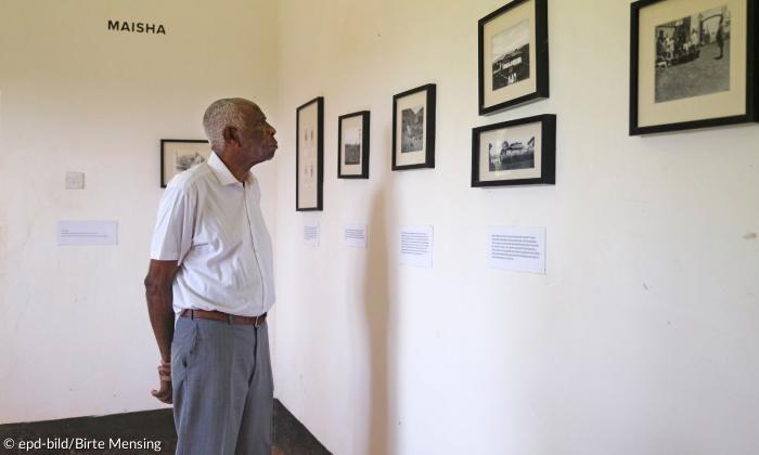Ein Mann schaut sich Fotos an, die an der Wand hängen