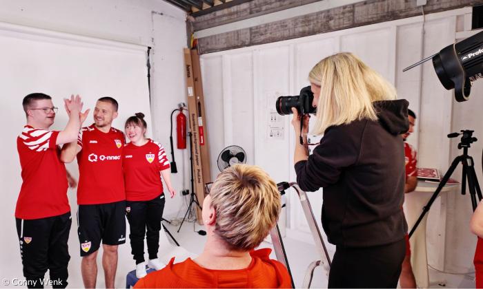 Eine Frau fotografiert drei Menschen in roten Hemden
