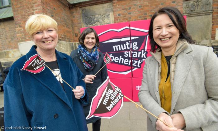 Drei Frauen mit Plakat und Fahnen