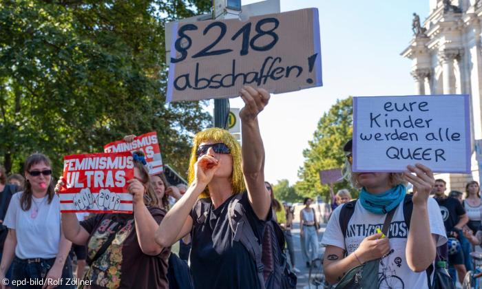 Menschen mit Schildern: "§ 218 abschaffen" und "Eure Kinder werden alle queer"