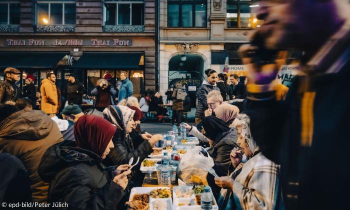 Menschen essen an Tischen, die auf der Straße stehen