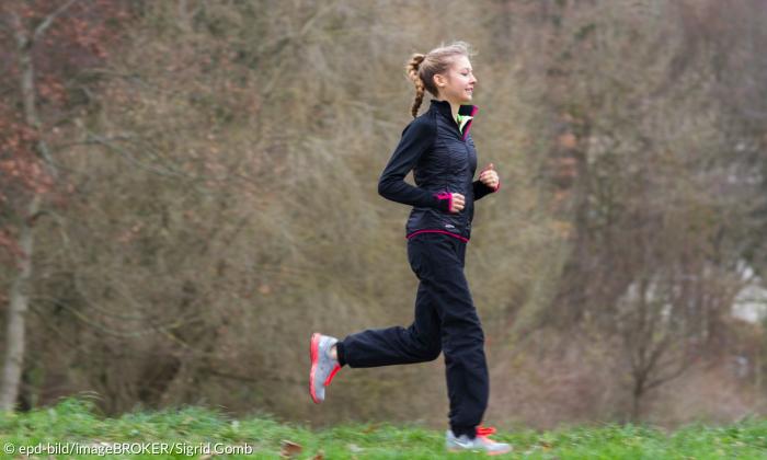 Eine Joggerin läuft über eine Wiese