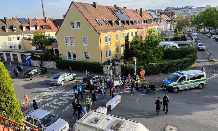 eine Schulstraße, darauf Menschen und ein Polizeiauto