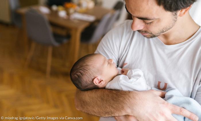 Ein Mann hält ein Baby auf dem Arm