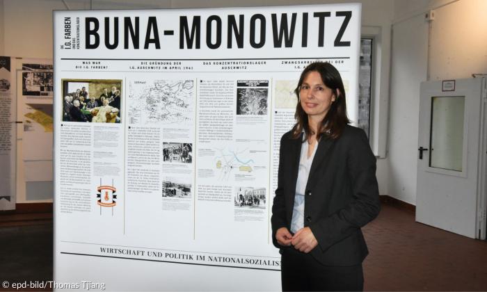 Eine Frau steht vor einem Ausstellungsplakat