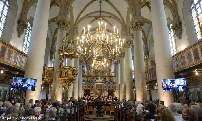 Eine große Kirche, gefüllt mit Menschen, an der Decke ein großer Kronleuchter