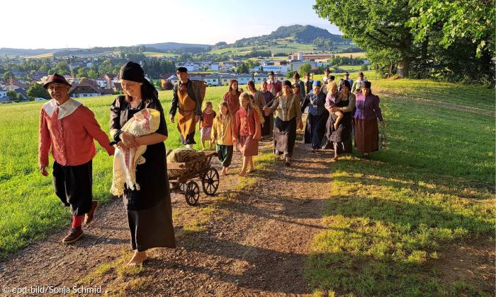 Menschengruppe läuft Feldweg entlang 