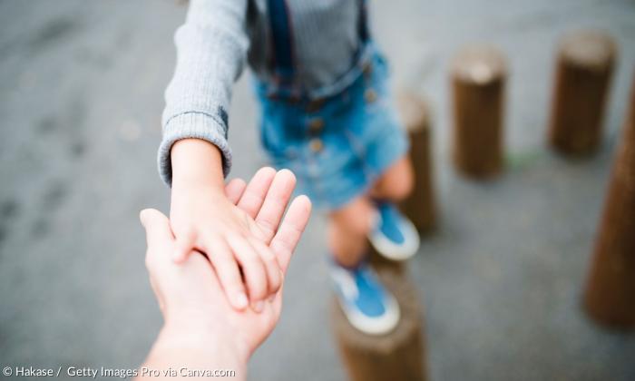 Kind hält Hand von Erwachsenden 