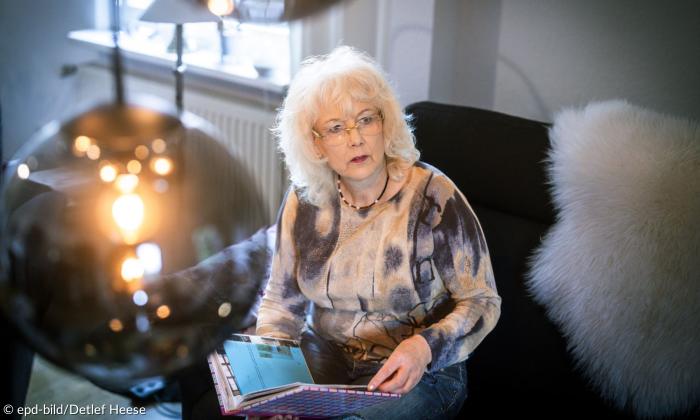 Ellen Kuhröber sitzt mit einem Fotoalbum auf ihrem Sofa. 