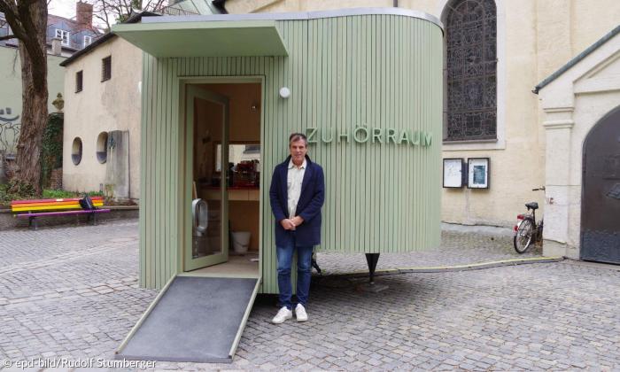 Ein Mann steht vor einem hölzernen Wagen