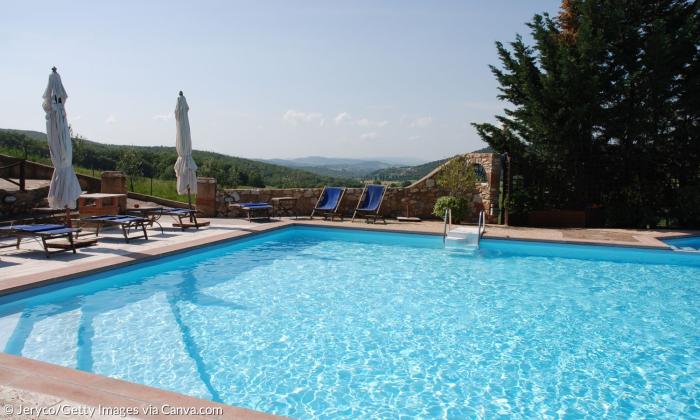 Ein Swimming Pool, dahinter Berge und ein blauer Himmel