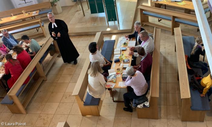 Gottesdienstbesucher sitzen an Bänken in der Kirche