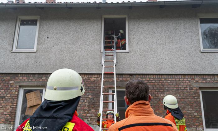 Feuerwehrleute an einer Leiter vor einem Haus