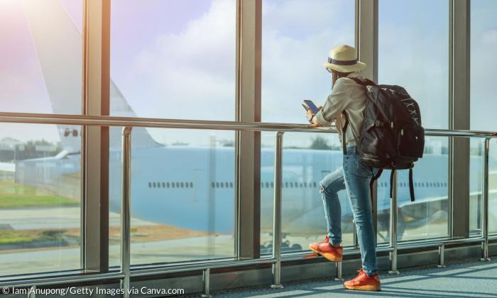 Eine Frau schaut am Flughafen durch ein Fenster auf ein Flugzeug