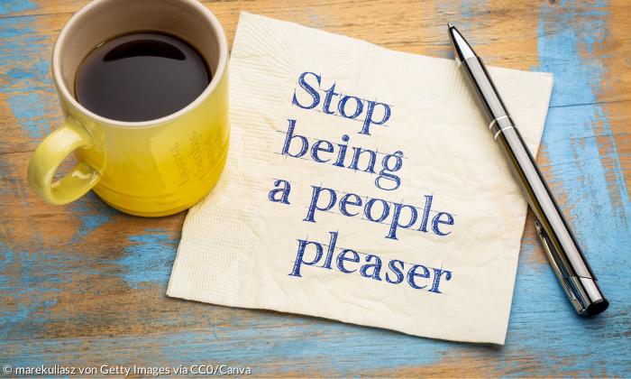 Ein Notizzettel mit der Aufschrift "Stop being a people pleaser" neben einer Kaffeetasse