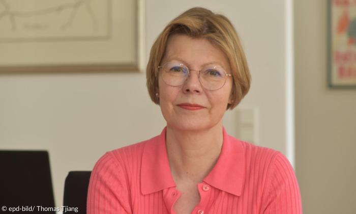 ältere Frau mit Brille und blondem Bob schaut in die Kamera