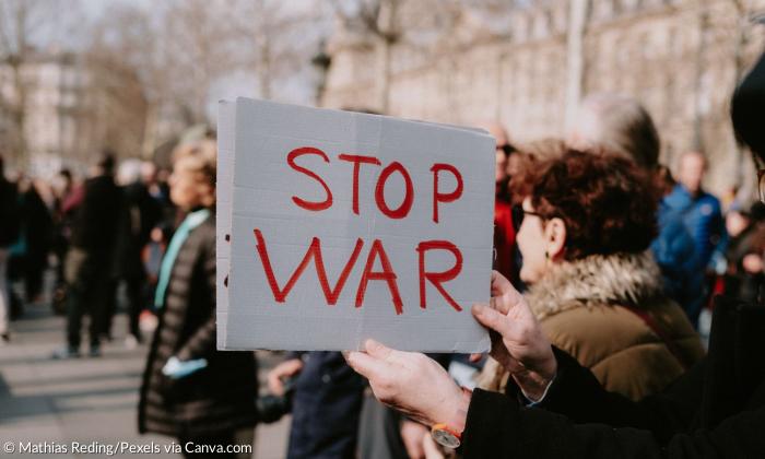 Eine Frau hält ein Schild, auf dem "Stop War" steht