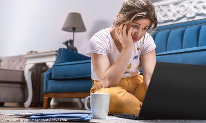 Eine Frau schaut verzweifelt auf ein Laptop