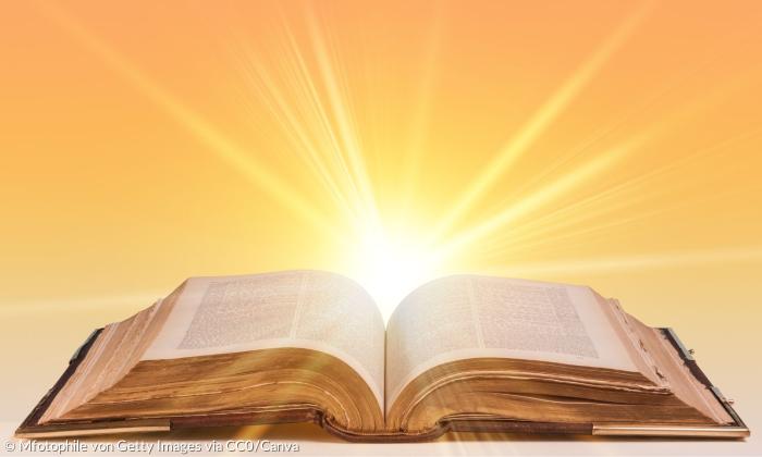 Hinter einer aufgeschlagenen Bibel geht die Sonne auf