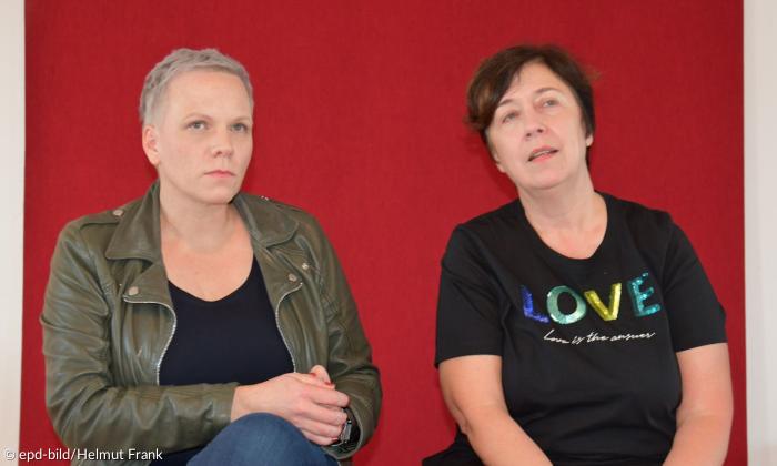 Zwei Frauen sitzen vor einer roten Wand