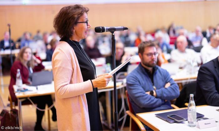 Eine Frau spricht an einem Mikrofon zum Podium