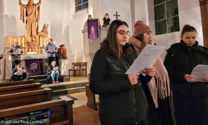 Junge Erwachsene stehen mit Zetteln in einer Kirche