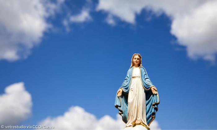 Eine Statue von Maria vor blauem Himmel mit weißen Wolken