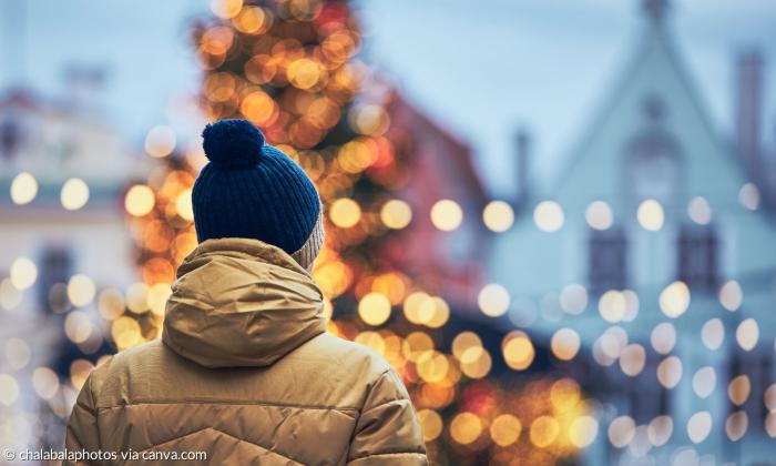 Ein Mann in Wintermantel steht vor strahlenden Lichtern