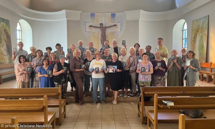 Viele Menschen stehen in einer Kirche und halten Gesangbücher