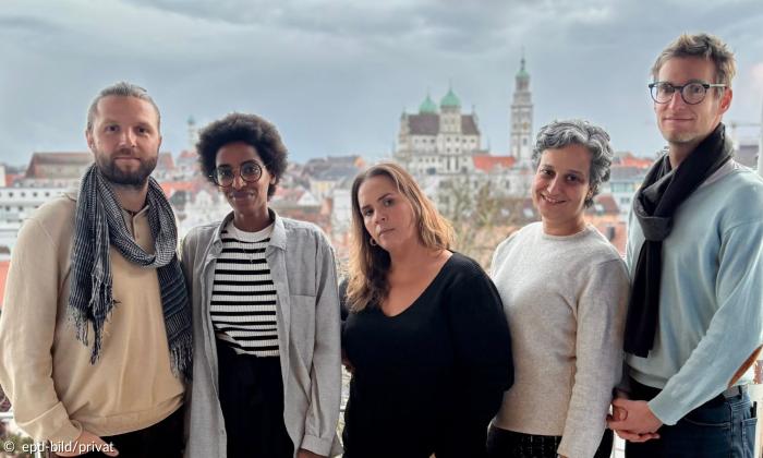 5 Menschen stehen vor dem Panorama von Augsburg