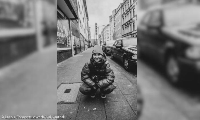 Schwarzweiß-Bild einer Frau, die auf einer Straße hockt