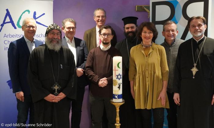 Neun Menschen stehen mit einer Kerze da