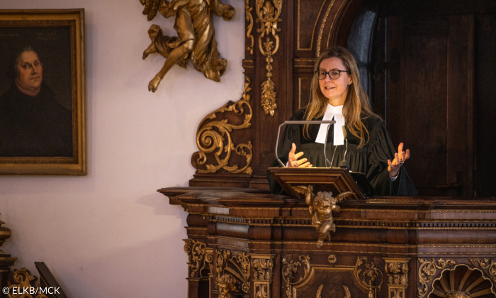Eine Frau im Talar spricht von einer Kanzel