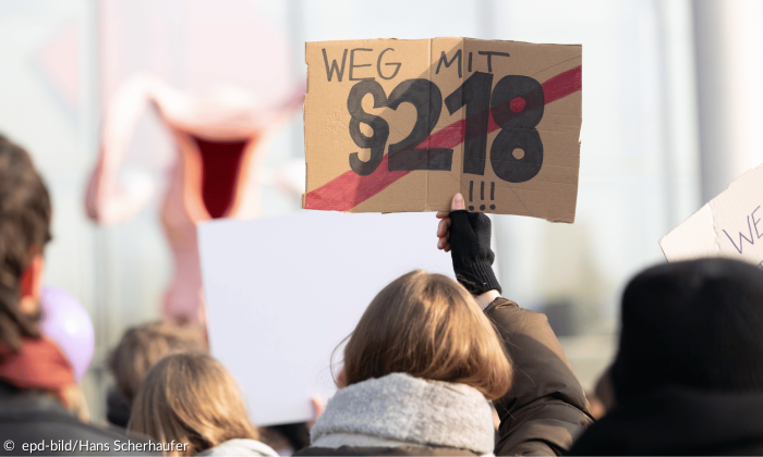 Eine Frau hält ein Schild auf einer Demonstration in die Höhe