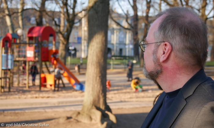 Ein Mann blickt traurig Richtung Spielplatz